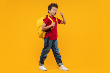 Full length studio shot of cute casually dressed confident African American kid walking with his...