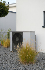 Heating pump in front of a new house with garden and some decorative plants