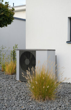 Heating pump in front of a new house with garden and some decorative plants