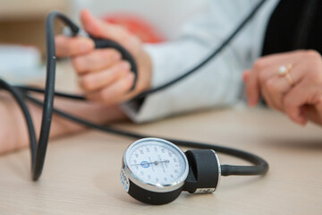 
Close up of a female doctor sitting at the desk in the office. Doctor measuring blood pressure of patient in hospital. Medical and healthcare concept.
