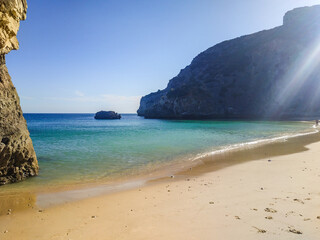 Ribeiro do Cavalo beach with sunlight above the cliff and reflected in the line between the sea and sand, Sesimbra PORTUGAL