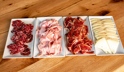 Embutido y queso en bandejas en mesa de madera rústica