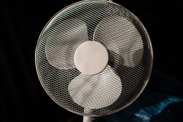Three-bladed fan in a protective mesh.