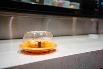 various types of sushi on conveyor belt in a Japanese restaurant. Shushi Go Round is a famous form of fast food in Asia, also known as sushi train.