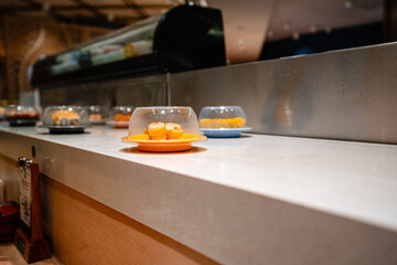 various types of sushi on conveyor belt in a Japanese restaurant. Shushi Go Round is a famous form...