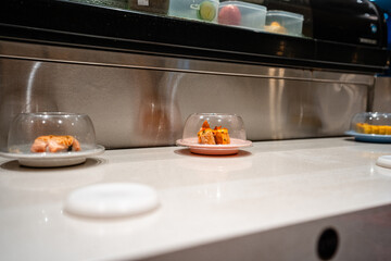 various types of sushi on conveyor belt in a Japanese restaurant. Shushi Go Round is a famous form of fast food in Asia, also known as sushi train.