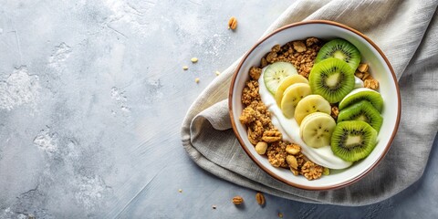 Flat lay of granola with yogurt, banana, and kiwi in a bowl on a light background