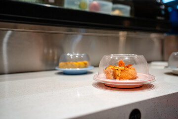 various types of sushi on conveyor belt in a Japanese restaurant. Shushi Go Round is a famous form...