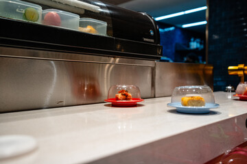 various types of sushi on conveyor belt in a Japanese restaurant. Shushi Go Round is a famous form of fast food in Asia, also known as sushi train.