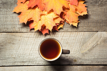 Cup of tea, colorful autumn leaves on wooden board. Fall still life, vintage style. Top view.