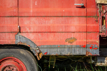 old rusty red car, paint peeling off due to rust. © Adam