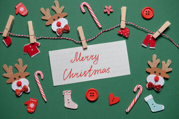 “Merry Christmas” caption. New Year decor (Christmas trees, reindeer, socks, lollipops) on green background. Top view. Place for text. Backgrounds and presentations