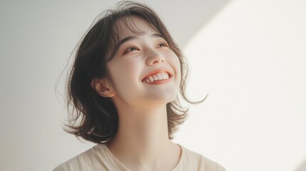 Naklejka premium Joyful Asian woman smiling against a minimalist white background with soft lighting and natural expressions