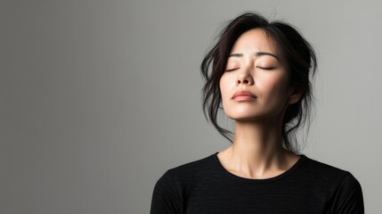 Fototapeta premium A minimalistic portrait of an Asian woman expressing sadness against a clean, neutral background with muted tones