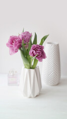 Pink tulips and cosmetics on white wooden background. Lipsticks