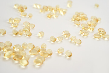 Scattered yellow capsules on white background show health and nutrition supplements