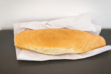 White bread whole loaf of Ikarian food with sesame seeds hand holding macro closeup on kitchen table at blue zone longevity