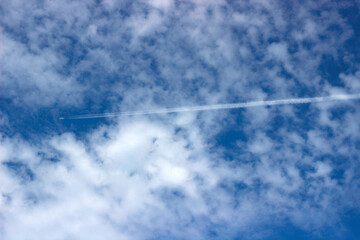 Airplane trail on the blue sky. Blue sky with clouds.