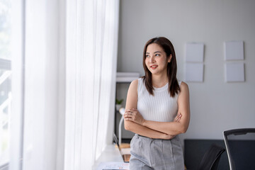 Young businesswoman is smiling and  looking through the window in office