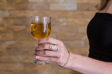 Smiling woman holds a glass of wine, in her beauty hand. Ring and bracelet on hand, luxurious life. Copy space
