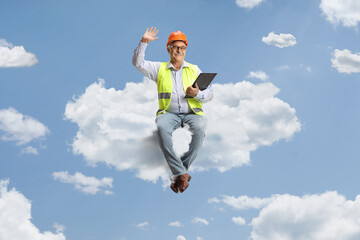 Full length portrait of a mature male engineer sitting on cloud and waving