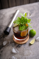 Cold Cuba Libre or Long island iced tea cocktail with brown rum, cola, mint, lime, muddler, jigger and glass