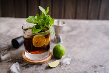 Cold Cuba Libre or Long island iced tea cocktail with brown rum, cola, mint, lime, muddler, jigger and glass