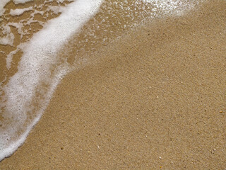 Fine golden sand covering a beach during a sunny day with clear skies, creating a serene and tranquil atmosphere for relaxation