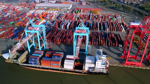 A busy container port in Liverpool England with a large cargo ship being loaded.