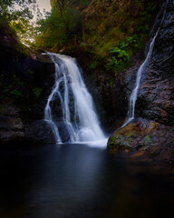 Naklejka premium Long exposure of two high mountain waterfalls end in a pond.