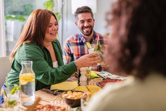 Woman passing cocktail to friend during lunch with friends