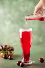 Boozy Refresing Cold Hard Cherry Cider in a Pint Glass and Bottle on wooden table. Copy space