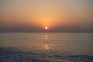 Beautiful scene of dusk or sunrise, with orange and blue colorful, over a calm water horizon at Mediterranean sea © Q