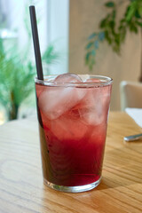 Large glass with a typical Spanish cocktail with red wine and soda called Tinto de Verano and straw on wooden table