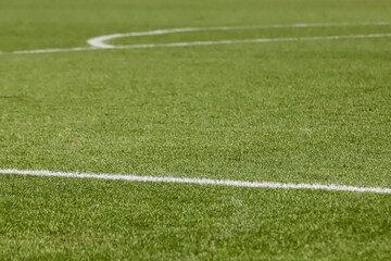 Football field with synthetic grass, with an angle below, highlighting the green of the lawn and some white lines.