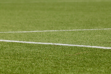 Obraz premium Football field with synthetic grass, with an angle below, highlighting the green of the lawn and some white lines.