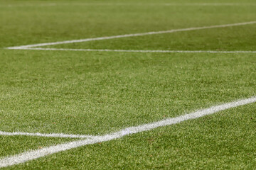 Obraz premium Football field with synthetic grass, with an angle below, highlighting the green of the lawn and some white lines.