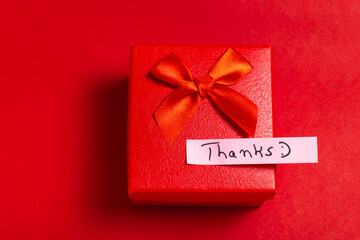 A red box with a red bow on top and a white note that says 