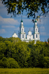 A beautiful white church featuring two green towers and a cross on top of it