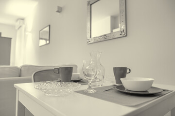 One-room bed and breakfast apartment, white interior design, open space: kitchen with dining table, living room with sofa