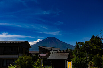 This is a beautiful image of Mount Fuji stretching up into the clear blue sky. White clouds can be...