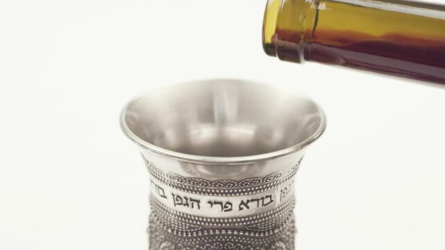 Slow motion of Kiddush cup filling up with wine, isolated over white, 4K video