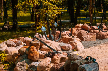 A large pile of rocks situated in a park with lush trees in the background