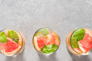 Refreshing grapefruit drink with mint leaves and ice on gray stone table