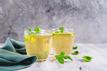 Organic basil lemonade in glasses and leaves on table