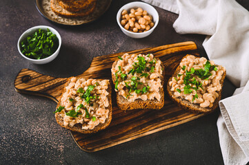 Bruschetta with mashed white beans and parsley on rye bread on a board