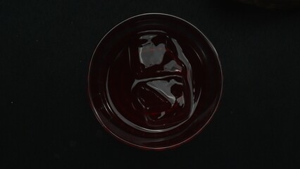 Top down view of bartender hand making and prepare Scarlet spritzer with black background. Close up...