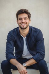 Fototapeta premium Smiling young man in business attire sitting on a bench with coffee in a bright, minimalist setting