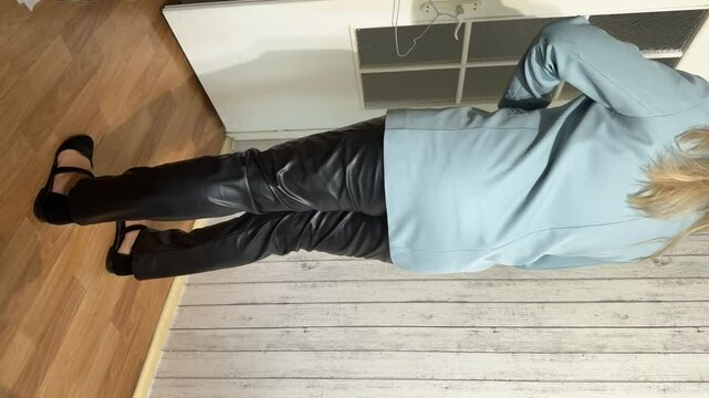 A woman in black leather pants and a blue classic blazer. She is showcasing a stylish look. Vertical video