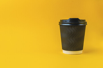 A black coffee cup sits on a yellow background